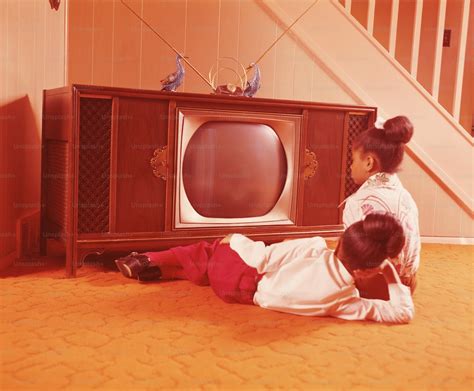 UNITED STATES - CIRCA 1970s: Two girls on living room floor, watching ...