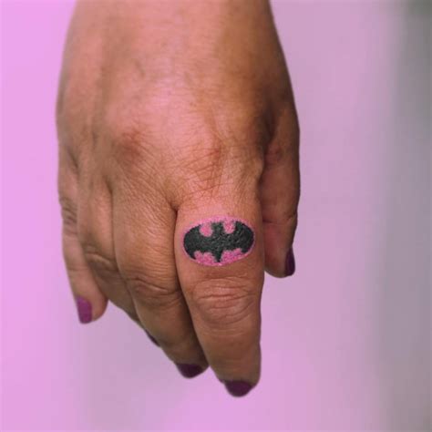 Hand poked Batman logo tattooed on the finger.