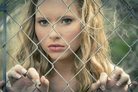 Portrait of young woman behind wire fence stock photo