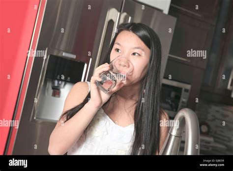 Teenager girl drinking water in the kitchen Stock Photo - Alamy