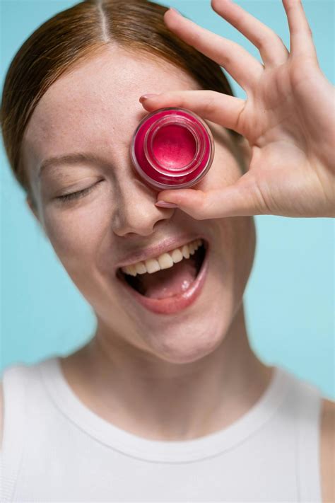 Smiling Woman Covering Her Eye With A Red Lipstick Cream · Free Stock Photo