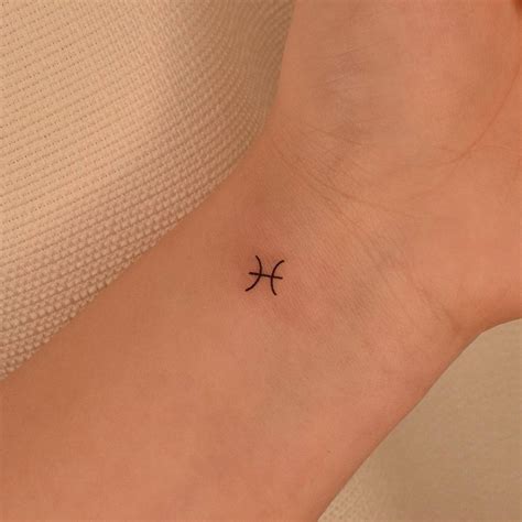 Minimalist pisces zodiac symbol tattoo on the wrist