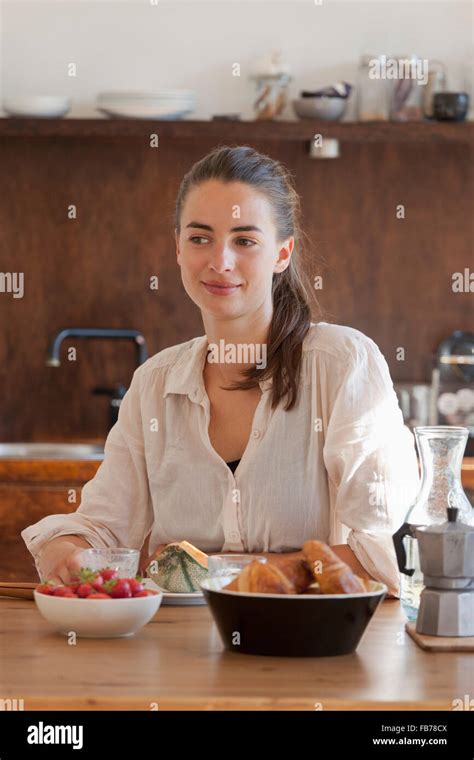 Young woman sitting at dining table with breakfast, smiling Stock Photo ...
