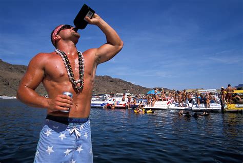 A young man drinks from a bottle of alcohol on a boat at Lake Havasu ...