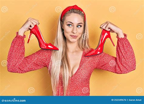 Young Caucasian Woman Holding Red High Heel Shoes Smiling Looking To ...