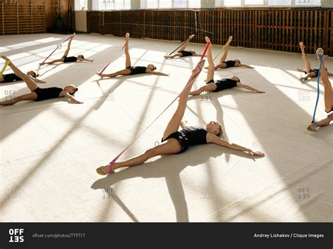 Group of young gymnasts are doing stretching exercises with colorful resistance bands while ...