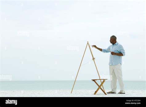 Senior man painting canvas at the beach, side view Stock Photo - Alamy