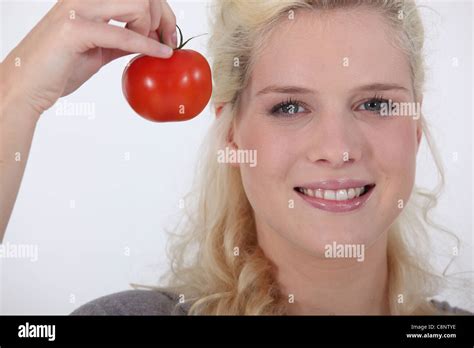 Blond woman with fresh tomato in hand Stock Photo - Alamy