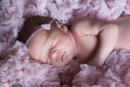 Royalty-Free photo: Baby lying on pink rosette cushion | PickPik