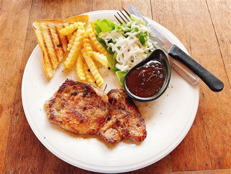 a white plate topped with meat, fries and coleslaw on top of a wooden table