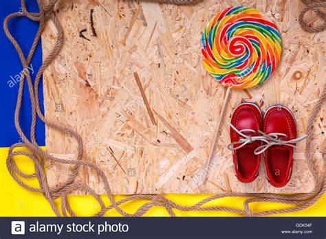 Small red boat shoes near big multi-colored lollipop and rope on wooden ...