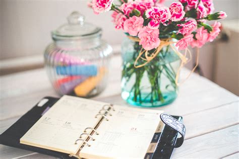 Personal organizer and pink flowers on desk · Free Stock Photo