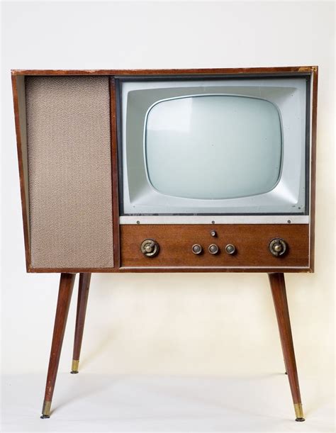 an old fashioned tv sitting on top of a wooden stand in front of a white wall