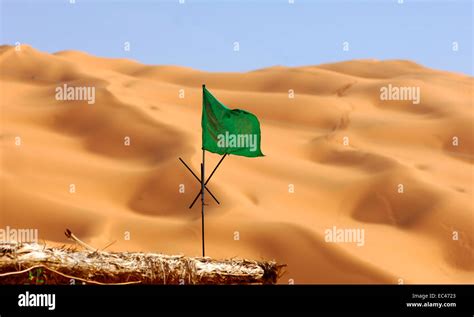 National flag of Libya fluttering over sand dunes of the Sahara desert ...