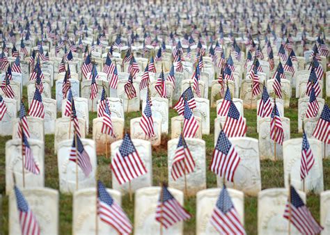 many american flags are placed next to headstones