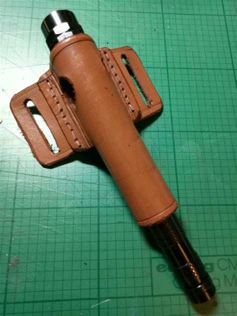Flashlight holster. Lght can be inserted through holes in the tube to ...