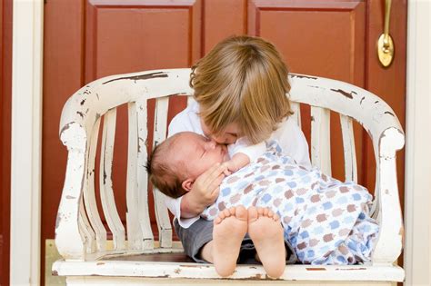 Boy Carrying and Kissing Baby Sitting on Chair · Free Stock Photo
