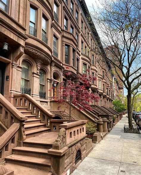 a row of brownstone townhouses on a city street with trees in the ...