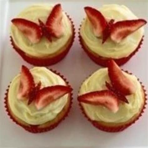 four cupcakes with strawberries on top are sitting on a square white plate