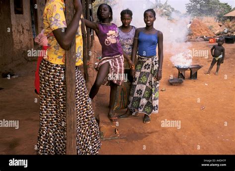 Young women pose whilst village life goes on around them. Bissau ...