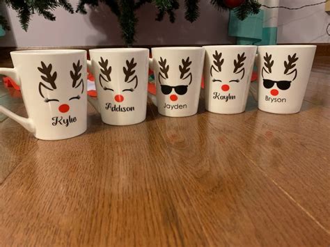 five coffee mugs with reindeer's on them sitting next to a christmas tree