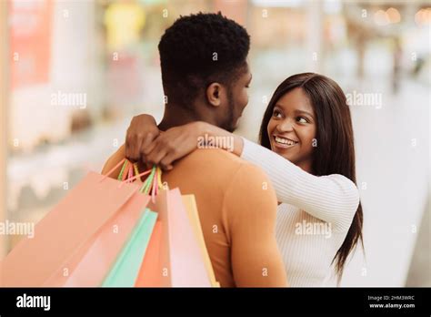 Happy black couple hugging and holding shopping bags Stock Photo - Alamy