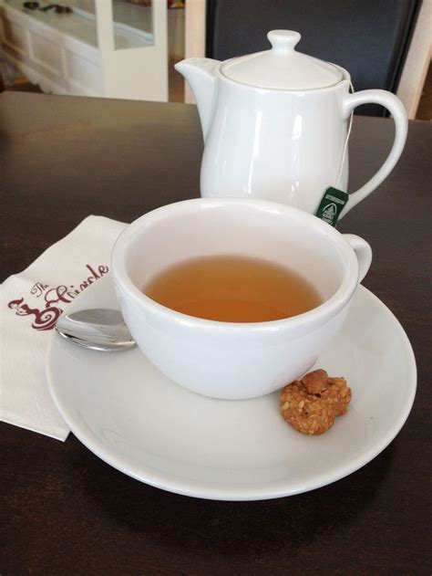 a cup of tea sits on a saucer next to a plate with a cookie