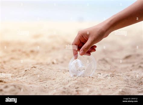 A hand cleaning and picking up a plastic glass trash on the beach Stock ...