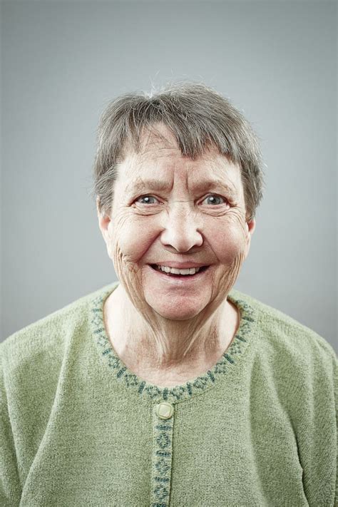 an older woman with gray hair and green shirt smiling at the camera ...