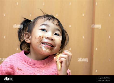 A happy toddler child eating chocolate ice cream in a cone with messy face Stock Photo - Alamy