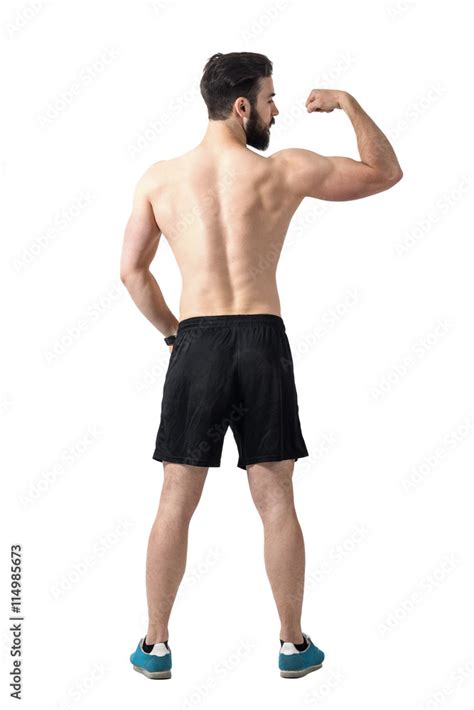 Rear view of young fit athlete flexing arm muscles. Full body length portrait isolated over ...