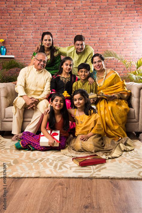 Portrait of happy Indian family in traditional wear sitting on sofa ...