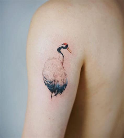 Red-crowned crane tattoo on the back of the left arm.