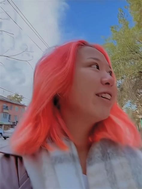 a woman with pink hair is looking up at the sky