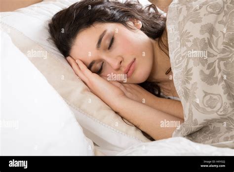 Young brunette woman sleeping in bed covered with a beige flowered ...