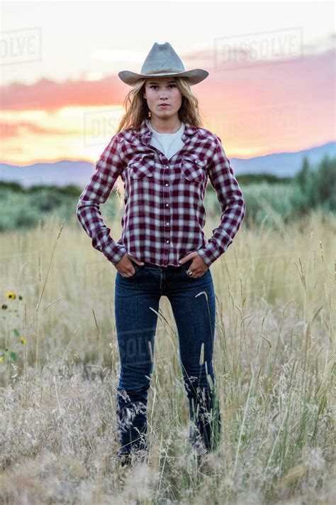 Portrait of serious Caucasian teenage girl wearing cowboy hat at sunset - Stock Photo - Dissolve