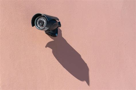 A modern black surveillance camera mounted on the wall closeup security and theft protection ...