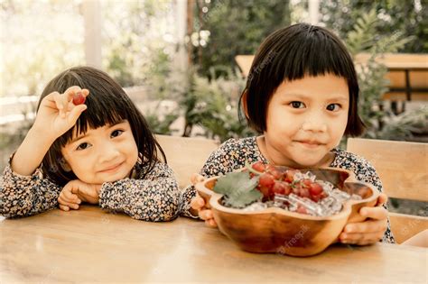 Premium Photo | Happy baby and kid wearing twin clothes sitting on the table with a plate of ...