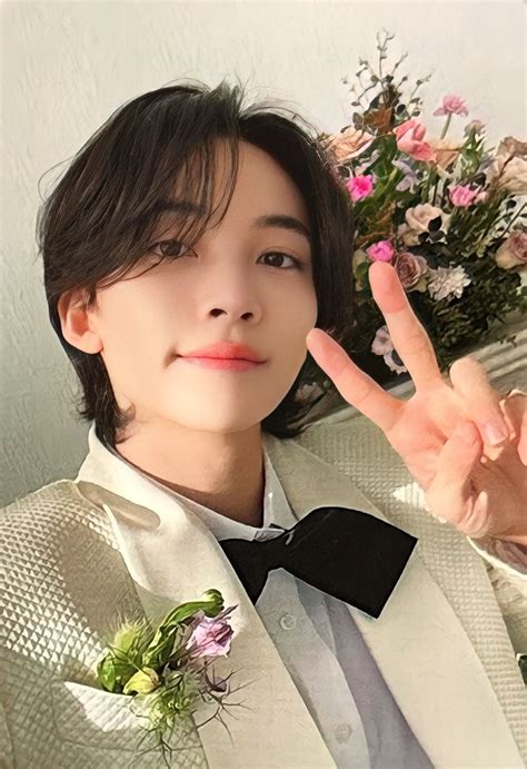 a man in a white suit and bow tie making the peace sign with his hand