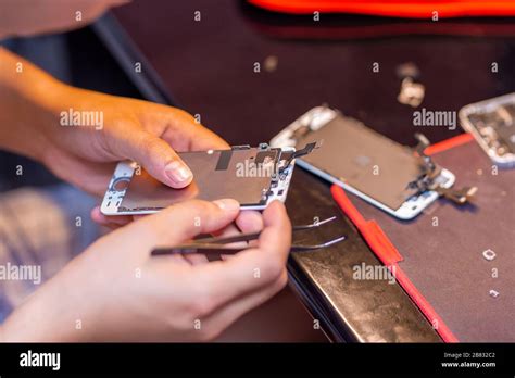 A man is repairing a mobile phone. In the frame, his hands and details of the device. repair ...