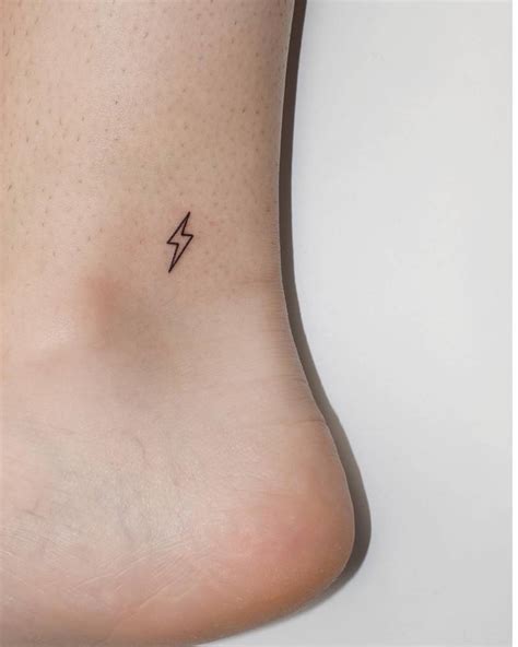 Tiny minimalistic lightning bolt tattoo located on the