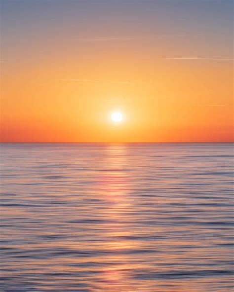 Download A stunningly beautiful sunset over the calm and inviting ocean. Wallpaper | Wallpapers.com