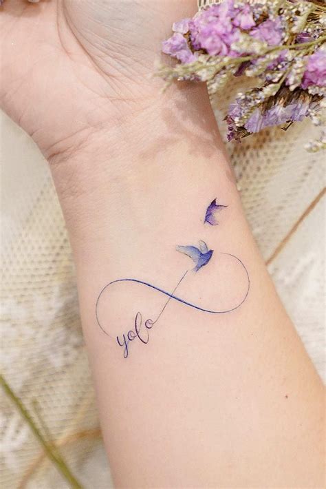 a woman's wrist with a tattoo on it and purple flowers in the background