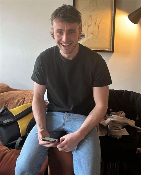 a man sitting on top of a couch holding a cell phone in his hand and smiling