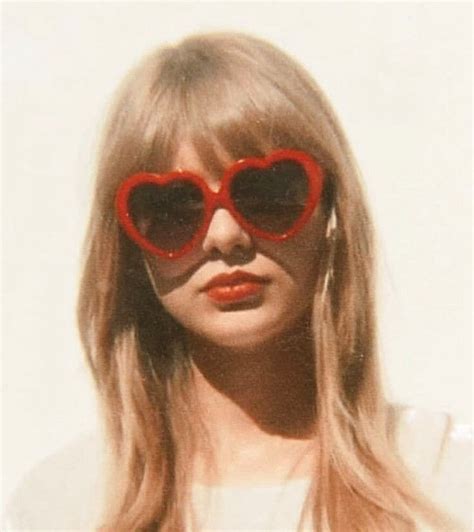 a woman with red heart shaped sunglasses on her face and long blonde hair in front of a white wall
