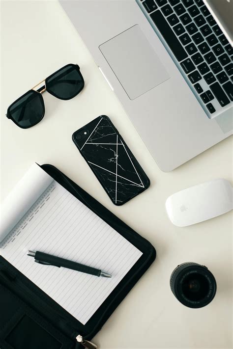 Top View Of A Pen On A Notepad, Sunglasses And Various Electronic Gadgets On A White Table Top ...