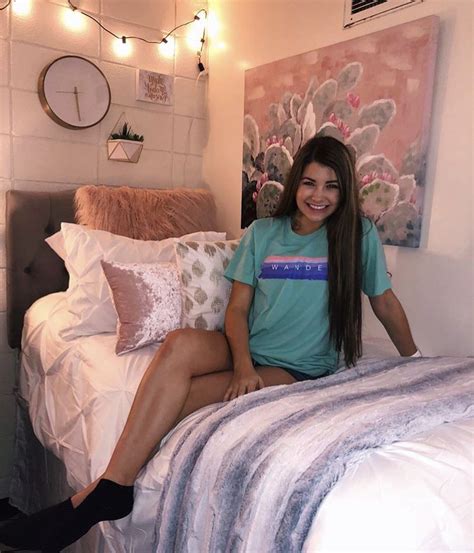 a woman sitting on top of a bed next to a wall with lights hanging above it