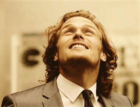 a man with long hair wearing a suit and tie looking up into the sky while smiling