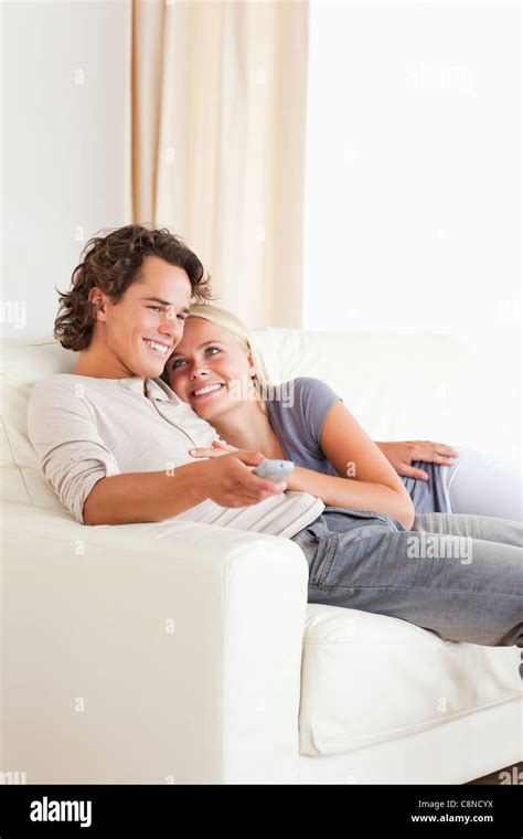 Portrait of a cute couple cuddling while watching TV Stock Photo - Alamy