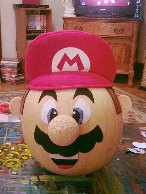 a large pumpkin with a mario bros hat on it's head, sitting in front of ...